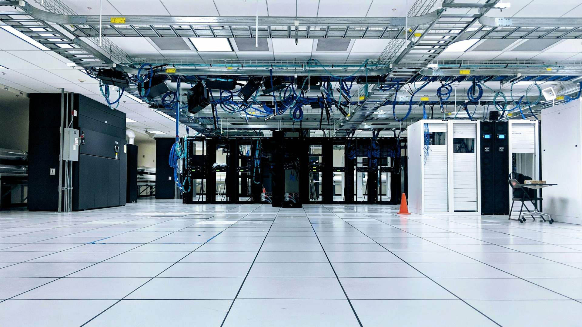 Raised-floor data hall with white floor tiles and overhead cable trays